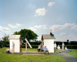 Inszeniertes Gruppenbild von Mitgliedern eines Astronomischen Vereins. Die Leute stehen und sitzen um und auf einem kleinen Haus für ein astronomisches Fernrohr