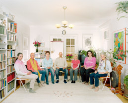 Inszeniertes Gruppenbild von Mitglieder eines Zirkels im Bereich spirituelle Mentalität. Die Männer und Frauen sitzen in einem Halbkreis in einem Zimmer.