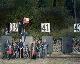 Inszeniertes Gruppenbild von Mitglieder von einem Schützenverein. Die Männer stehen mit ihren Gewehren vor dem Kugelfang.