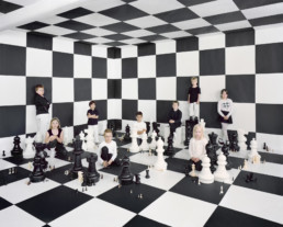 Inszeniertes Gruppenbild von Kinder in einem Raum mit Schachfiguren und Schachfeldern.
