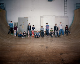 Inszeniertes Gruppenbild von Jugendlichen mit ihren Skateboards in einer Halfpipe.
