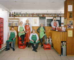 Inszeniertes Gruppenbild von Mitglieder von einem Bierbrau-Verein. Sie sitzen und stehen in Ihrer Brauküche. Ringsum Harassen und Brauutensilien