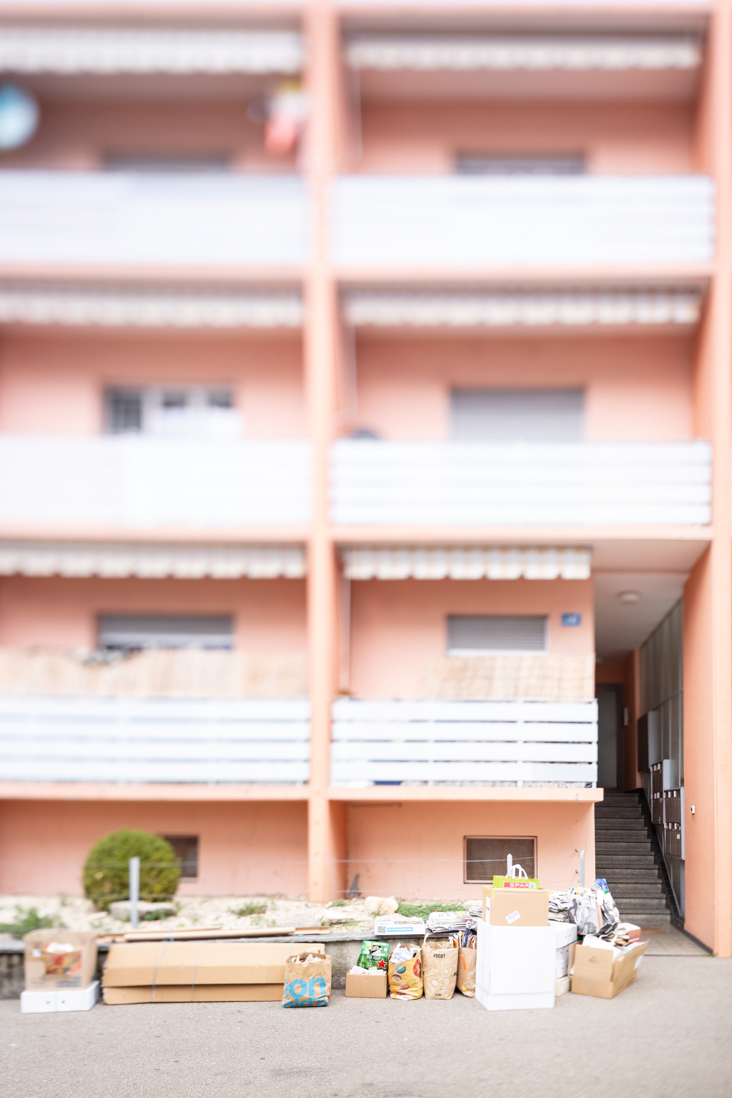 Vor einem rosaroten Mehrfamilienhaus steht das Altpapier zum abholen bereit.